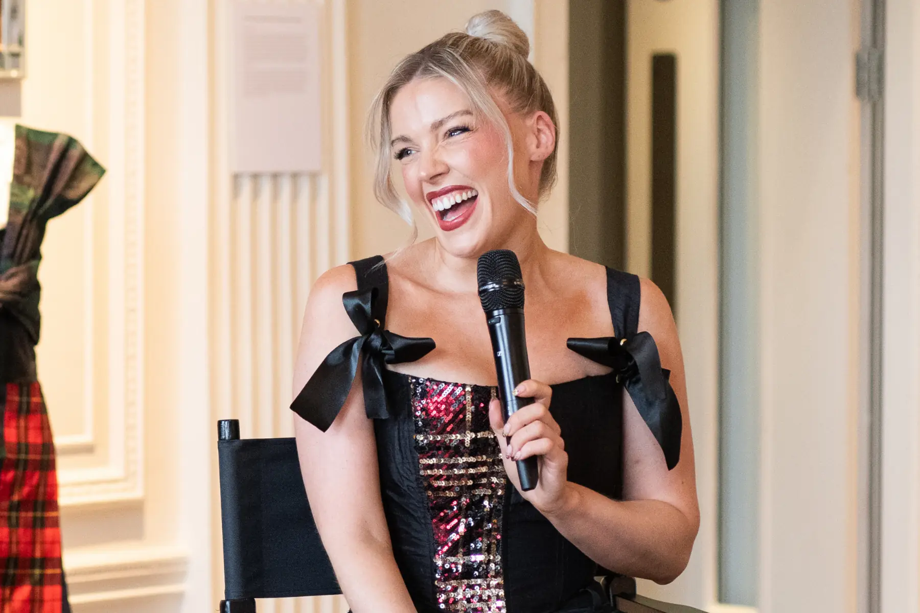Scottish designer Siobhan Mackenzie smiling and speaking into a microphone during her Blythswood Square Hotel residency launch in Glasgow