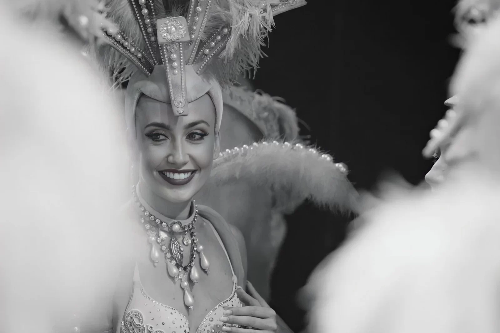 Fallon Robertson smiling in elaborate showgirl costume with feathered headdress, performing as artistic director and choreographer at Trocadero’s, Crossbasket Castle in Scotland.
