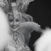 Fallon Robertson smiling in elaborate showgirl costume with feathered headdress, performing as artistic director and choreographer at Trocadero’s, Crossbasket Castle in Scotland.