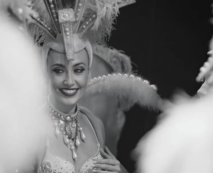 Fallon Robertson smiling in elaborate showgirl costume with feathered headdress, performing as artistic director and choreographer at Trocadero’s, Crossbasket Castle in Scotland.