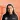 Portrait of Mae MacInnes, general manager of Mharsanta in Glasgow, wearing a branded shirt with an orange-toned background featuring the River Clyde, Finnieston Crane and Squinty Bridge.