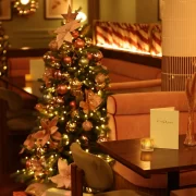 A decorated Christmas tree with lights and pastel ornaments inside The Delphine restaurant in Glasgow.