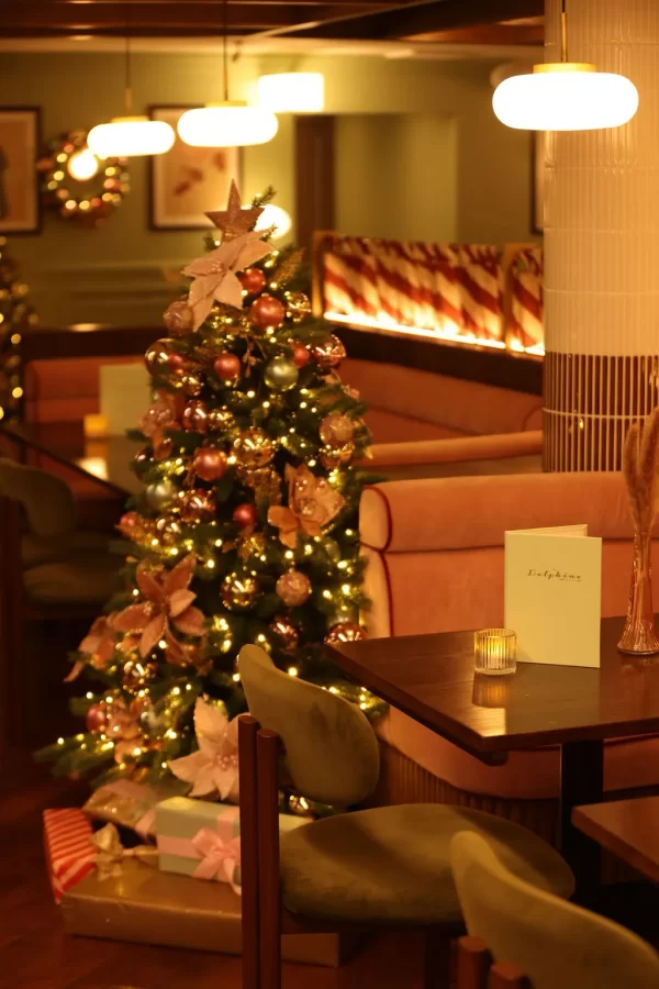 A decorated Christmas tree with lights and pastel ornaments inside The Delphine restaurant in Glasgow.