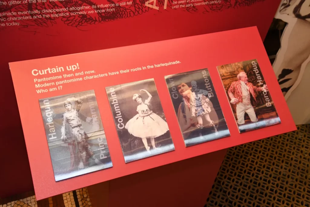 Display panel at the Glasgow City Chambers panto exhibition featuring images of Harlequin, Columbine, Buttons and Baron Hardup, highlighting pantomime’s historic characters.