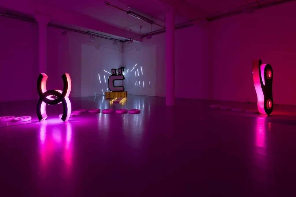 Illuminated sculptures by artist Jamie Cooper displayed in a purple-lit gallery space at Fruitmarket Warehouse in Edinburgh.