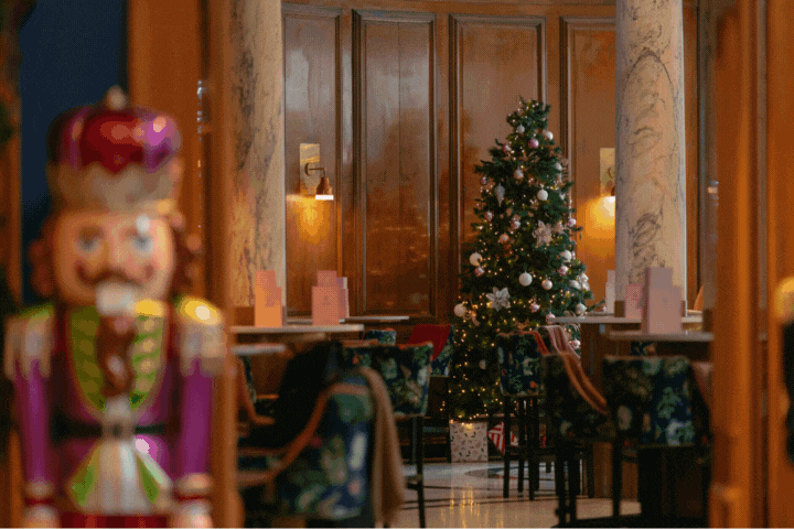 A warmly lit Champagne Central at voco Grand Central Glasgow featuring a decorated Christmas tree, elegant seating and festive décor during the hotel’s seasonal afternoon tea.